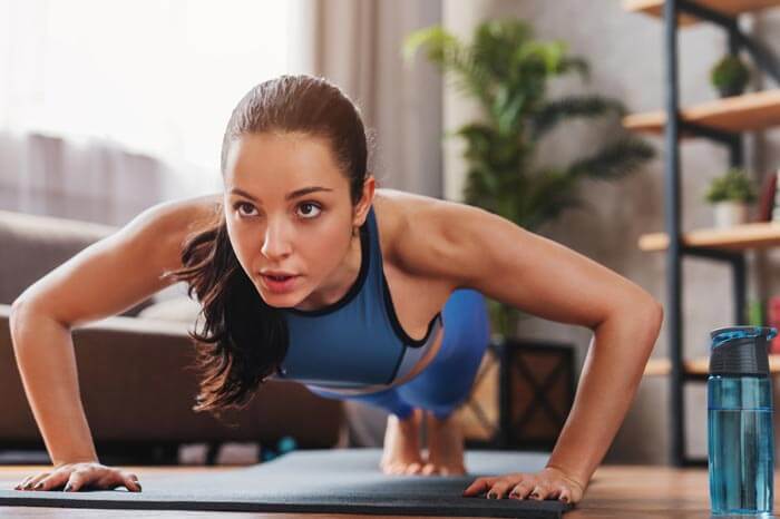 joven hispana haciendo push ups mientras entrena en casa