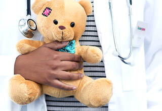 Médico sonriente con un oso de peluche en las manos